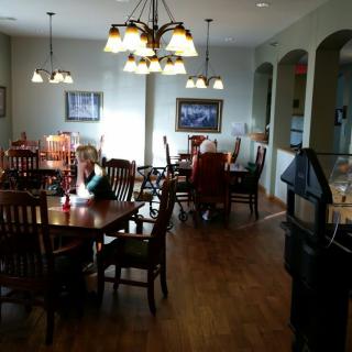 A cozy dining area with wooden tables and chairs, illuminated by chandeliers.