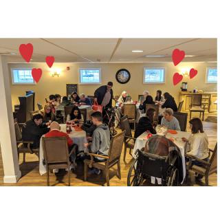 A community gathering with people seated at tables in a decorated room.