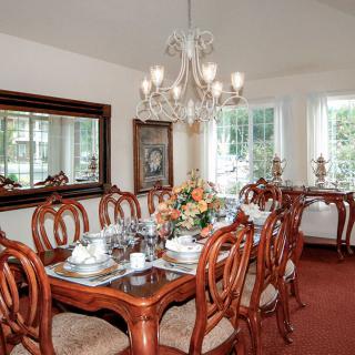A beautifully decorated dining room with a chandelier above the table and elegant wooden furniture.
