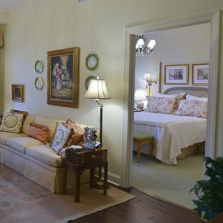 A cozy living room with a view into a bedroom, featuring soft lighting and elegant decor.