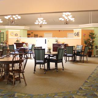 A spacious dining area with neatly arranged tables and chairs, featuring elegant lighting fixtures.