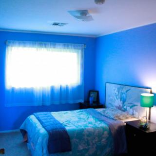 A cozy bedroom with bright blue walls and a softly lit lamp.