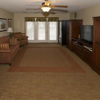A spacious living room with a large TV, comfortable sofas, and a big carpet.