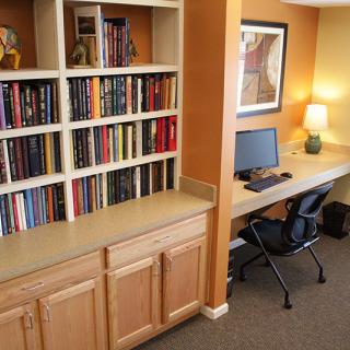 A cozy home office with a well-stocked bookshelf and a tidy computer workstation.