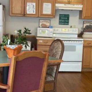 A cozy kitchen and dining area with wooden cabinets, a table, chairs, and various appliances.
