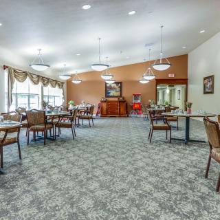 A spacious dining area with neatly arranged tables and chairs, featuring large windows and elegant lighting.