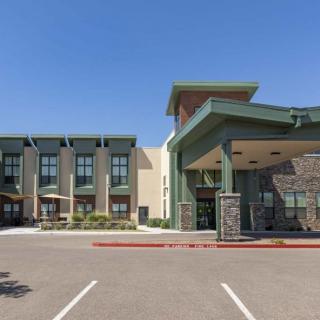 A modern hotel building with a spacious parking area and a prominent entrance.