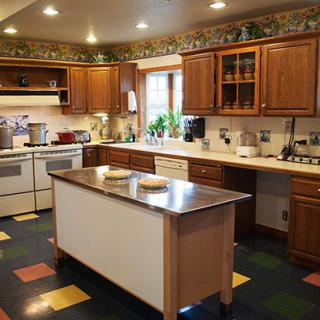 A cozy kitchen featuring wooden cabinets, a central island, and colorful tiled flooring.