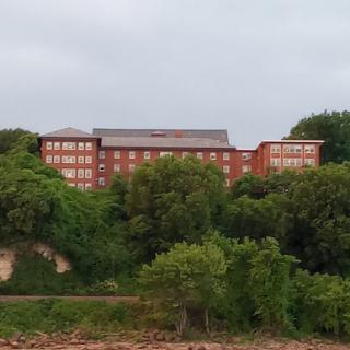 A multi-story brick building nestled among lush greenery.
