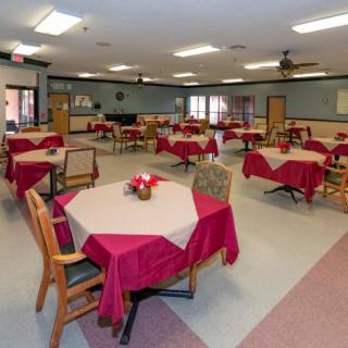 A spacious dining area with multiple tables covered in red tablecloths.