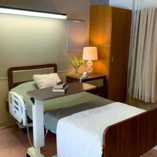 A neatly arranged hospital room with a bed, side table, and lamp.
