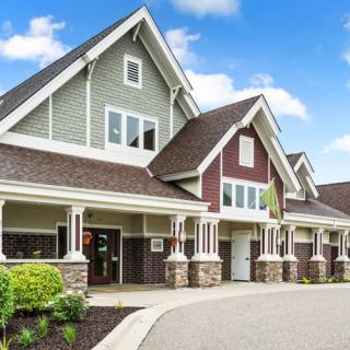 A modern suburban house with a large gable roof and stone accents.