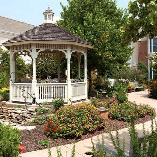 A charming white gazebo surrounded by a beautifully landscaped garden.