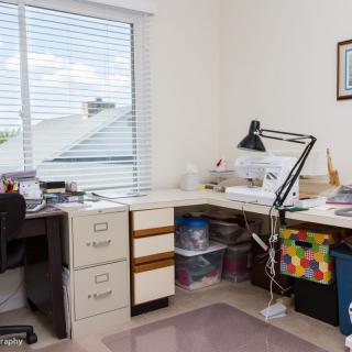 A well-organized home office with a desk, lamp, and filing cabinets near a window.