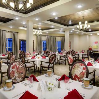 An elegantly decorated restaurant dining room with formal table settings and chandeliers.