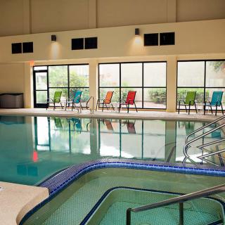 An indoor swimming pool with colorful chairs lined up along large windows.