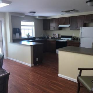 A modern kitchen with wood flooring and dark cabinets.