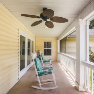 A cozy porch with rocking chairs and a ceiling fan, perfect for relaxation.