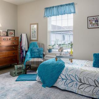 A cozy bedroom with turquoise accents and natural light pouring in through the window.