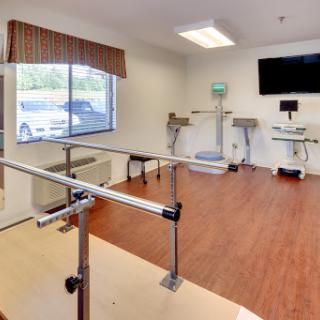A well-equipped physical therapy room featuring parallel bars and various exercise equipment, designed for rehabilitation.