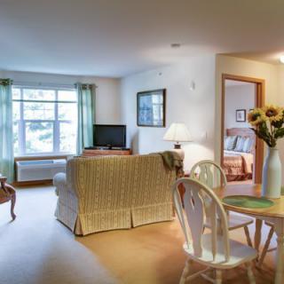 A cozy living room with a dining area, featuring a sofa, television, and wooden furniture.