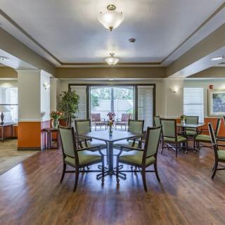 A spacious and elegantly designed dining area with wooden flooring, featuring tables and chairs under soft ceiling lights.