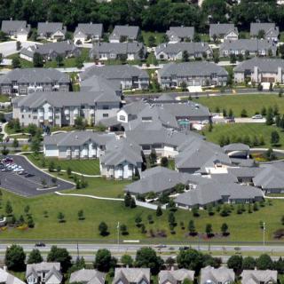 Aerial view of a suburban residential neighborhood with evenly spaced houses and green areas.