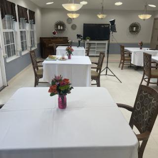 A well-arranged dining area featuring neatly set tables with white tablecloths and floral centerpieces.