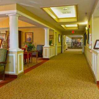 A brightly lit hallway with a comfortable seating area and carpeted floors.