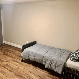 A minimalist bedroom with a single bed and wooden flooring.