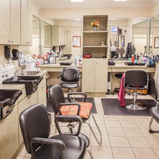 An empty hair salon with chairs and mirrors lined up, ready for customers.