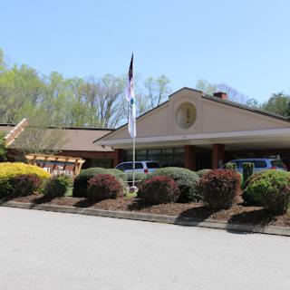 A well-maintained building surrounded by colorful bushes and a clear blue sky.