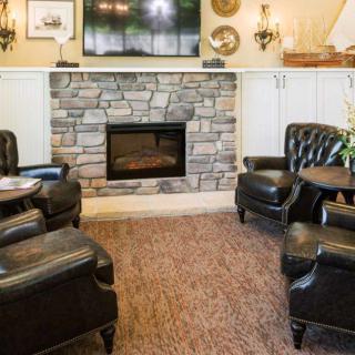 Cozy living room with a stone fireplace and leather armchairs.