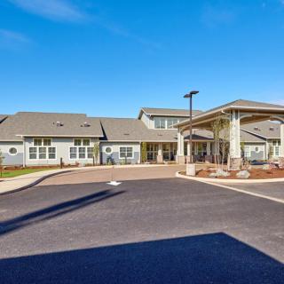 A modern residential building with a driveway and main entrance under a clear blue sky.