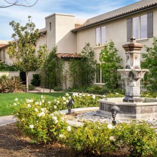 A charming house features a beautifully landscaped garden with a central fountain.