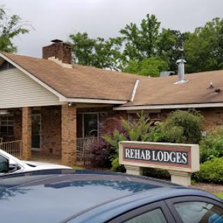 A view of the Rehabilitation Lodges with a welcoming sign and greenery surrounding the building.