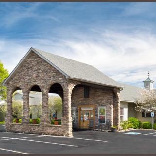 Stone building with arches and a parking lot under a clear sky.