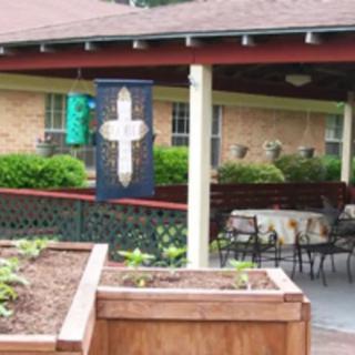 A community garden space with outdoor seating and a decorative cross banner.