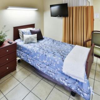 A cozy bedroom with a single bed, television, and nightstand.