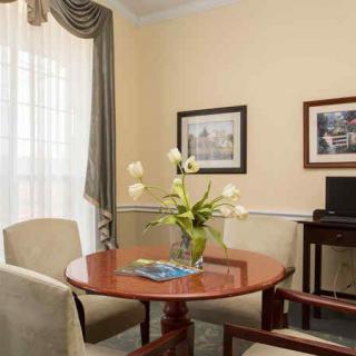 A cozy living room with a round wooden table, surrounded by chairs and decorated with a vase of flowers.