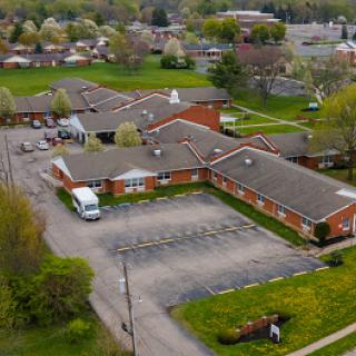 An aerial view of a residential complex with a parking lot surrounded by green spaces.