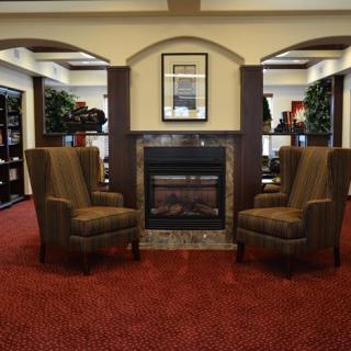 A cozy seating area with two armchairs facing a fireplace in a library setting.