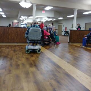 A waiting area with people and a wheelchair on a wooden floor.