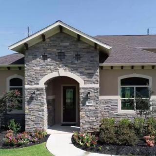 A modern house with a stone facade and well-maintained landscaping.