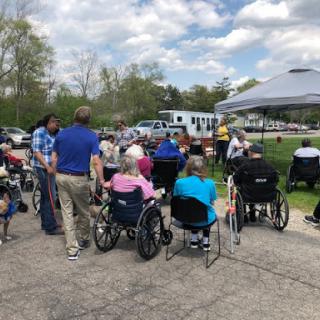 A community gathering for elderly individuals enjoying the outdoors, surrounded by caregivers and healthcare services.
