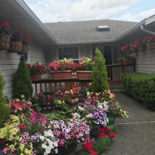 A charming house with a vibrant flower garden and planters on the deck.