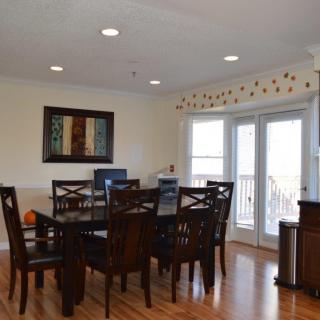 A well-lit dining room with a large table, chairs, and artwork on the wall.
