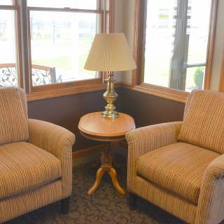 A cozy seating area with two armchairs, a small round table, and a lamp by the window.