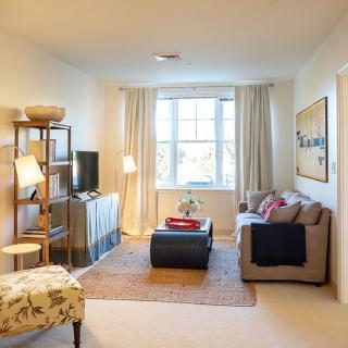 A cozy living room with a sofa, ottoman, and decorative elements under soft lighting.
