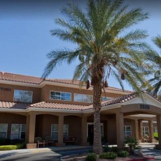 Entrance of a residential building with palm trees on a sunny day.